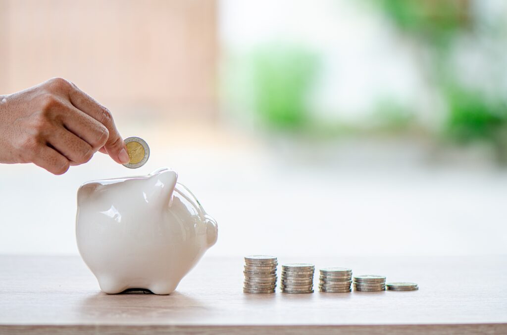 hand of man drop coin into piggy bank arranged as graph.